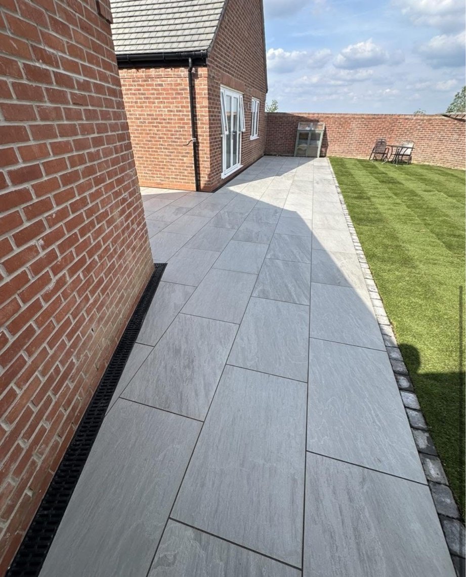 Grey porcelain patio beside new lawn